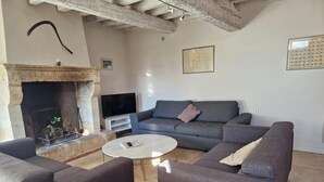 Una sala de estar con chimenea, un sofá, una mesa de centro y una televisión.