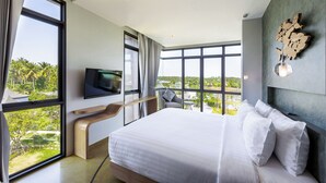 A modern hotel room with a large bed, a TV mounted on the wall, and a view of greenery outside. - Na Tree Tara Riverside Resort Amphawa Damnoensaduak (Bang Khonthi)