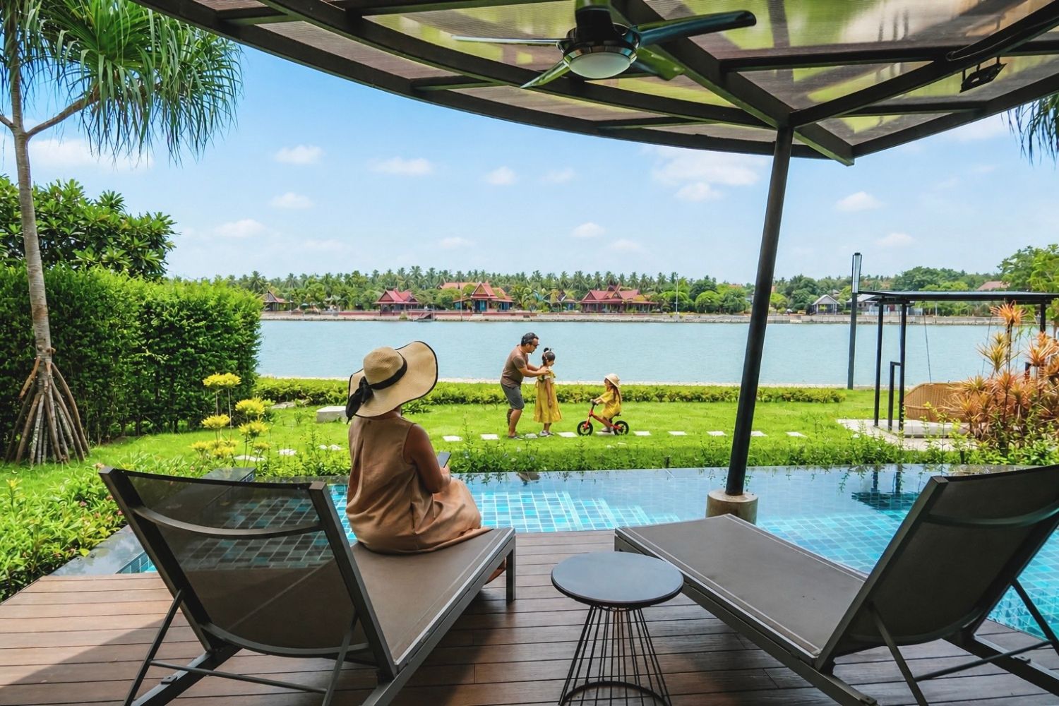 A poolside area with lounge chairs, a covered seating area, and a view of a lake with buildings in the background.