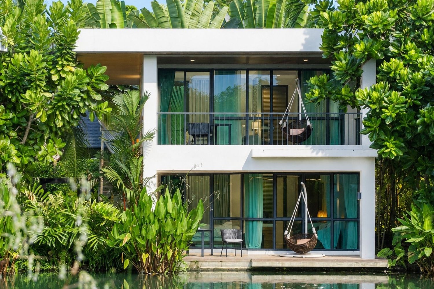 Una casa moderna de dos pisos con piscina, rodeada de exuberante follaje.
