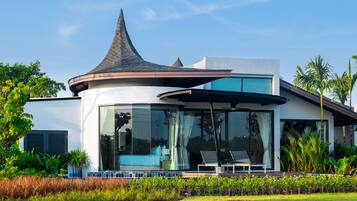 A modern house with a curved roof, large windows, and a well-maintained garden.