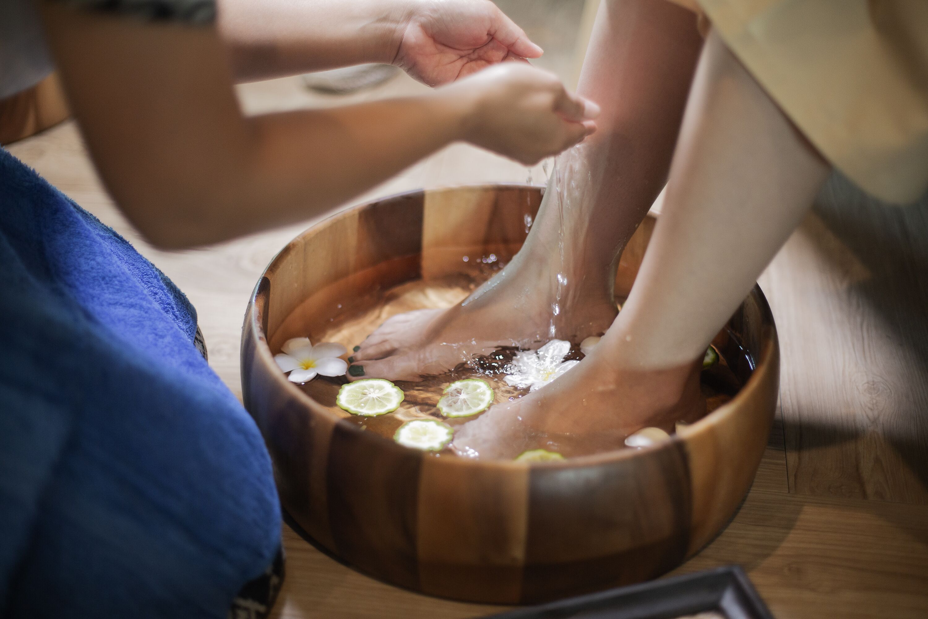 Un récipient en bois rempli d’eau et de tranches de citron vert, utilisé pour les bains de pieds.