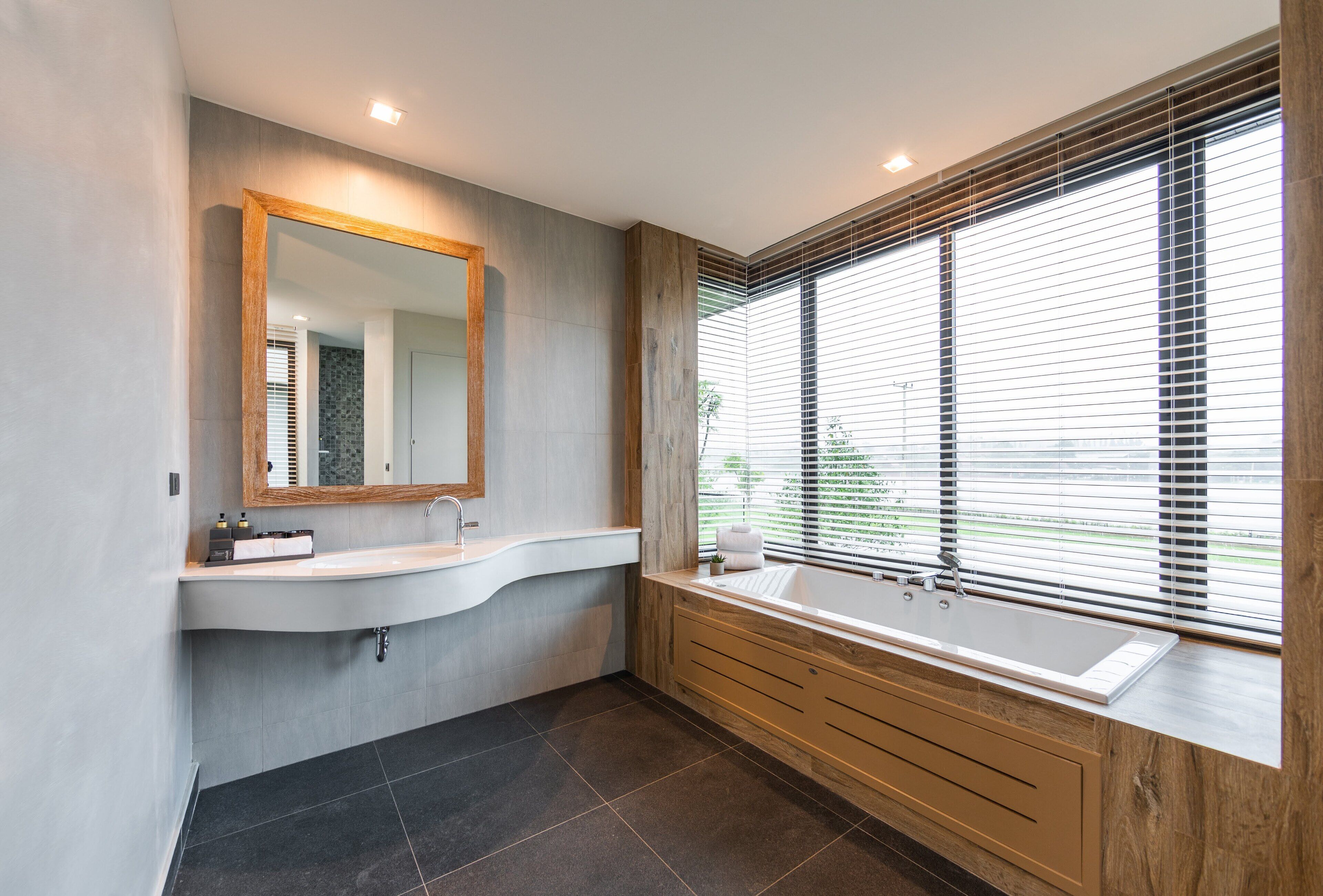 Un baño moderno con un espejo grande, una bañera independiente y un tocador con lavamanos.