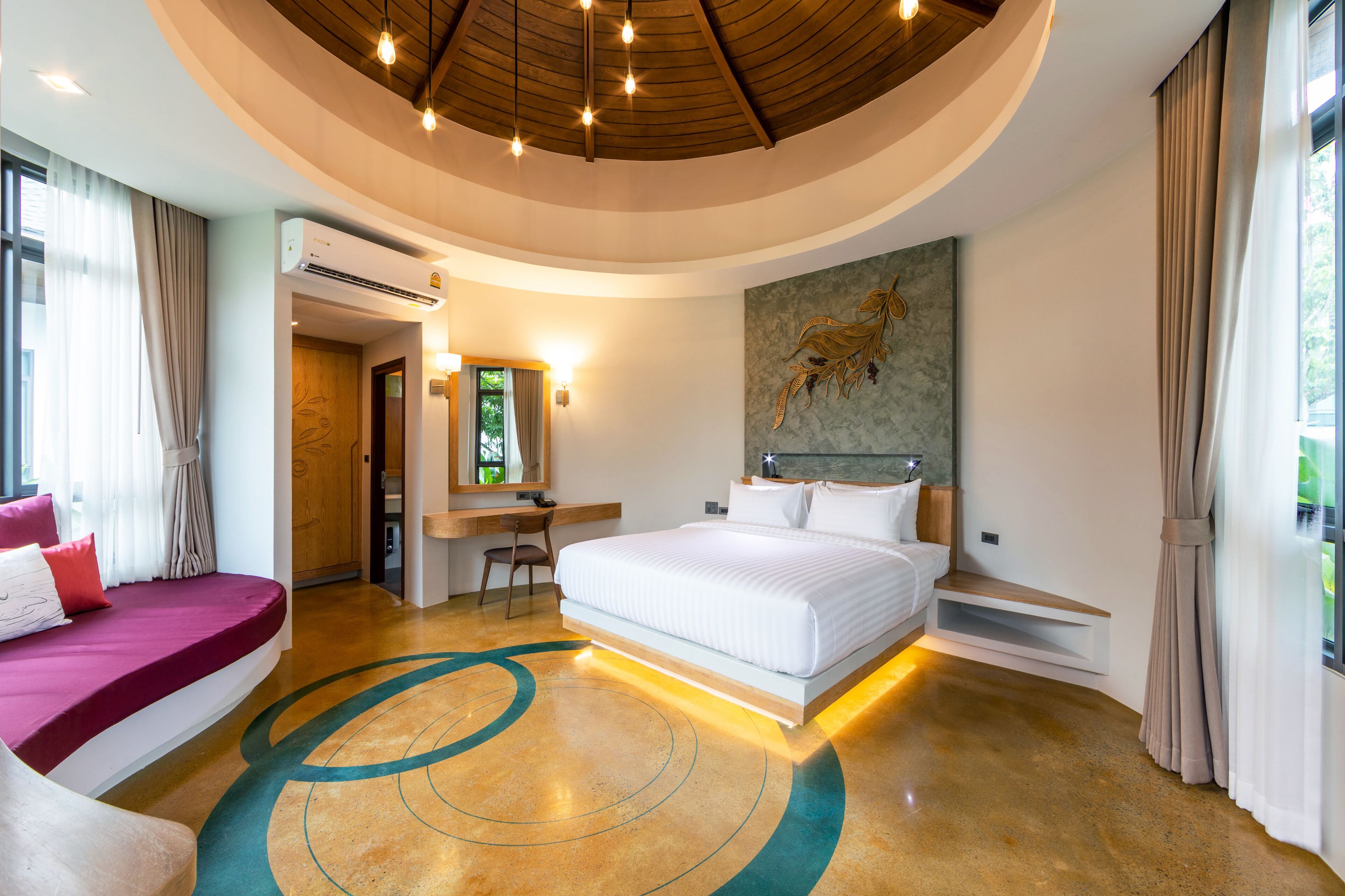 Een moderne hotelkamer met een gebogen plafond, een groot bed, een bureau en een zithoek.
