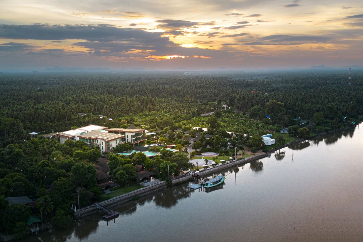 An aerial view of a lakeside property with a large building, a dock, and surrounding greenery.