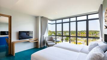 A hotel room with a large bed, a TV, a desk, and a view of the landscape.
