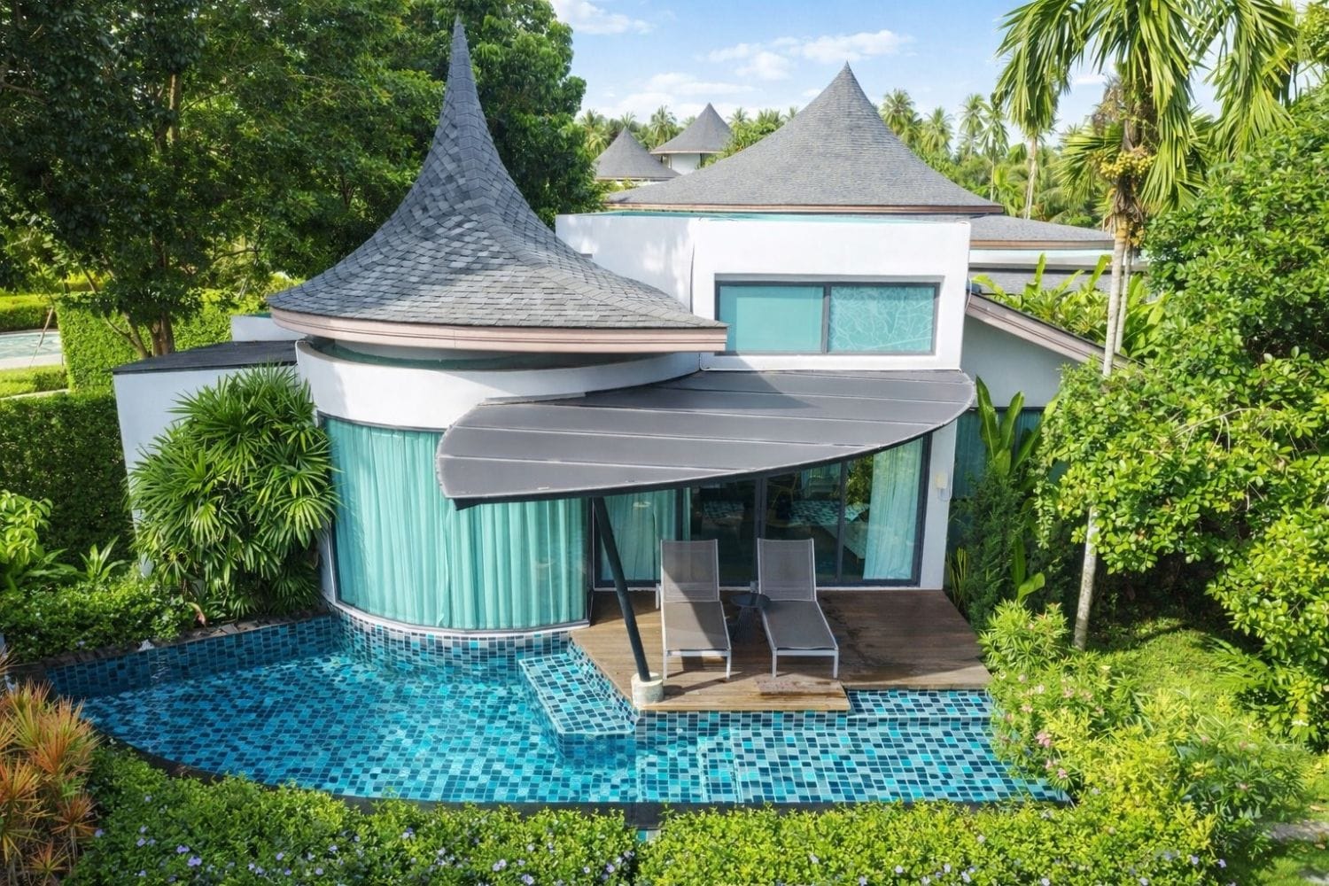 A modern house with a swimming pool, a covered patio, and lush greenery.