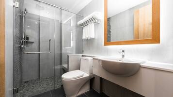 A modern bathroom with a glass-enclosed shower, a white toilet, a sink, and a large mirror.