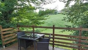 A wooden deck with a table and chairs, surrounded by a wooden fence and lush greenery. - Sarlat double room (VITRAC)