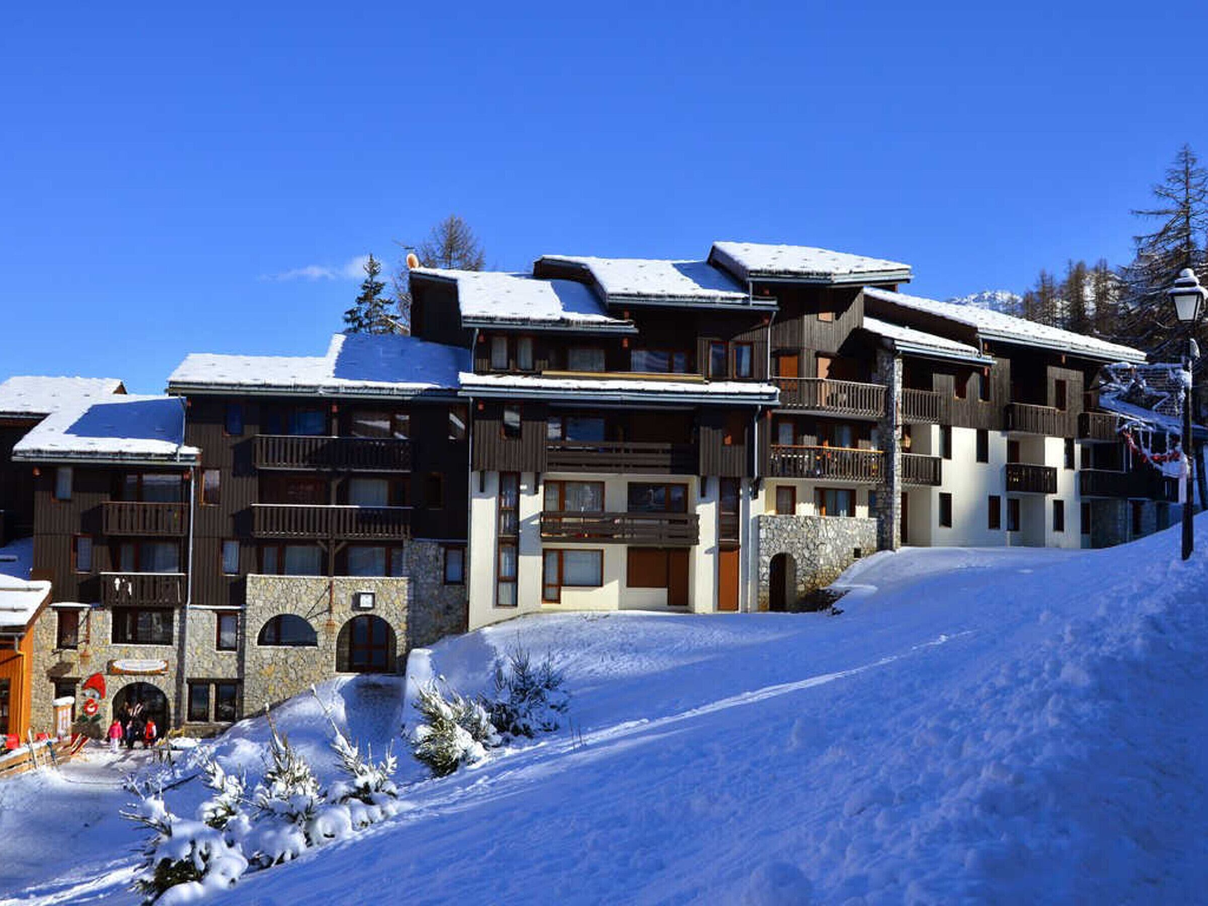 Un edificio di una stazione sciistica a più piani con balconi e facciata in pietra.
