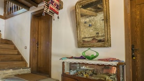 A wooden staircase leading to a room with a stone floor, a wooden cabinet with glass doors, and a large mirror on the wall. - Birgi Yeni Gelin Evi (Odemis)
