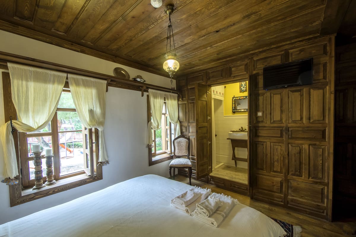 Una stanza in legno con un letto, una sedia, un lavandino e uno specchio.