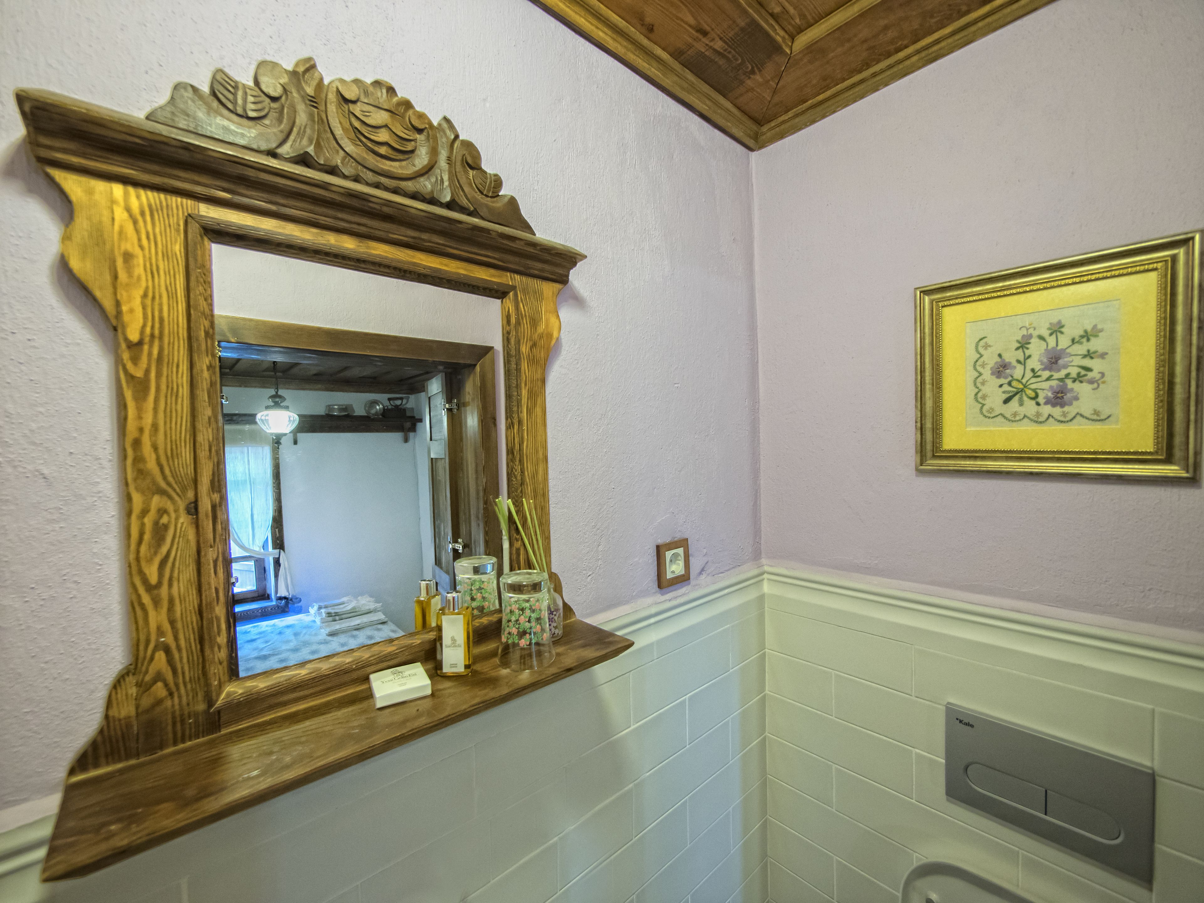 Un baño con tocador de madera, un espejo, una obra de arte floral enmarco y una pared de azulejos.