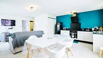 Un appartement moderne comprenant un coin repas, une kitchenette et un salon.
