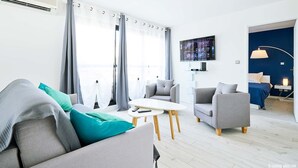 Een moderne woonkamer met een bank, fauteuils, een salontafel en een televisie.
