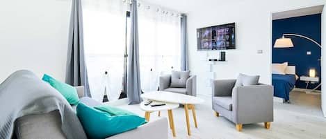Un salon moderne avec un canapé, des fauteuils, une table basse et un téléviseur.