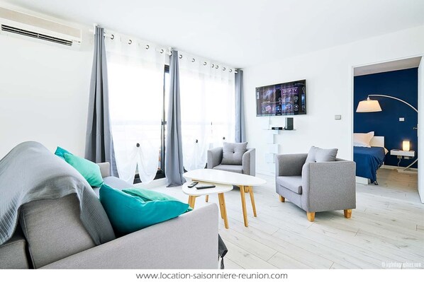 A modern living room with a sofa, chairs, a coffee table, and a TV.