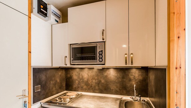 A compact kitchen with a built-in microwave, a sink, and a small refrigerator. - Divisible studio for 3, near shops and slopes, free parking, balcony (Bellentre)