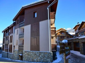A multi-story building with a stone base, wooden upper floors, and balconies. - Cozy apartment for 5 in Montchavin, near the slopes (Bellentre)