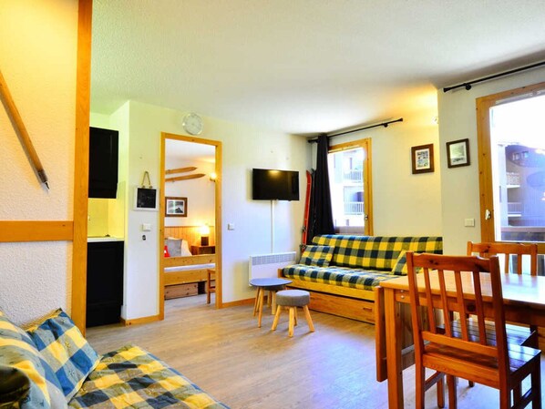 A cozy living room with a sofa, a dining table, and a TV.