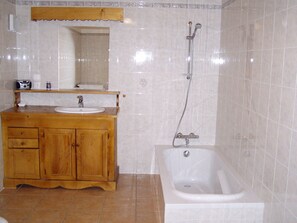 A bathroom with a wooden vanity, a sink, a mirror, and a bathtub. - chalet la grange du villard le criou (Samoëns)