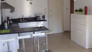 A modern kitchen with a microwave, bar stools, and a white cabinet. - T2 Very quiet, close to beaches and town center, sea and mountain views (L'île-Rousse)