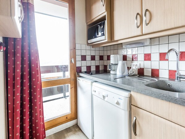 A compact kitchen with a dishwasher, a coffee maker, and a microwave.