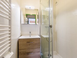 Bathroom features a glass-enclosed shower, a vanity with a single drawer, and a mirror above.