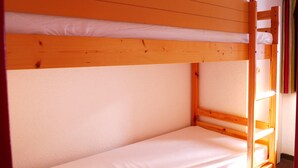 A bunk bed with a wooden frame and white bedding. - 2-Room Apartment with Balcony, Ski Access, and Free Parking - Montchavin Les Coches (Bellentre)