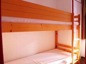 A bunk bed with a wooden frame and white bedding.