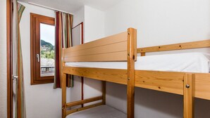 Ein Etagenbett mit Fenster und Vorhängen, ein Stuhl und Blick auf ein Gebäude.