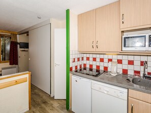 Compact kitchen with microwave, dishwasher, and cabinetry.