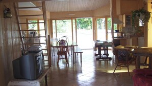 A spacious living area with a television, wicker furniture, and a view of the outdoors. - Homerez - Villa in Saint Hilaire de Riez (Saint Hilaire de Riez)