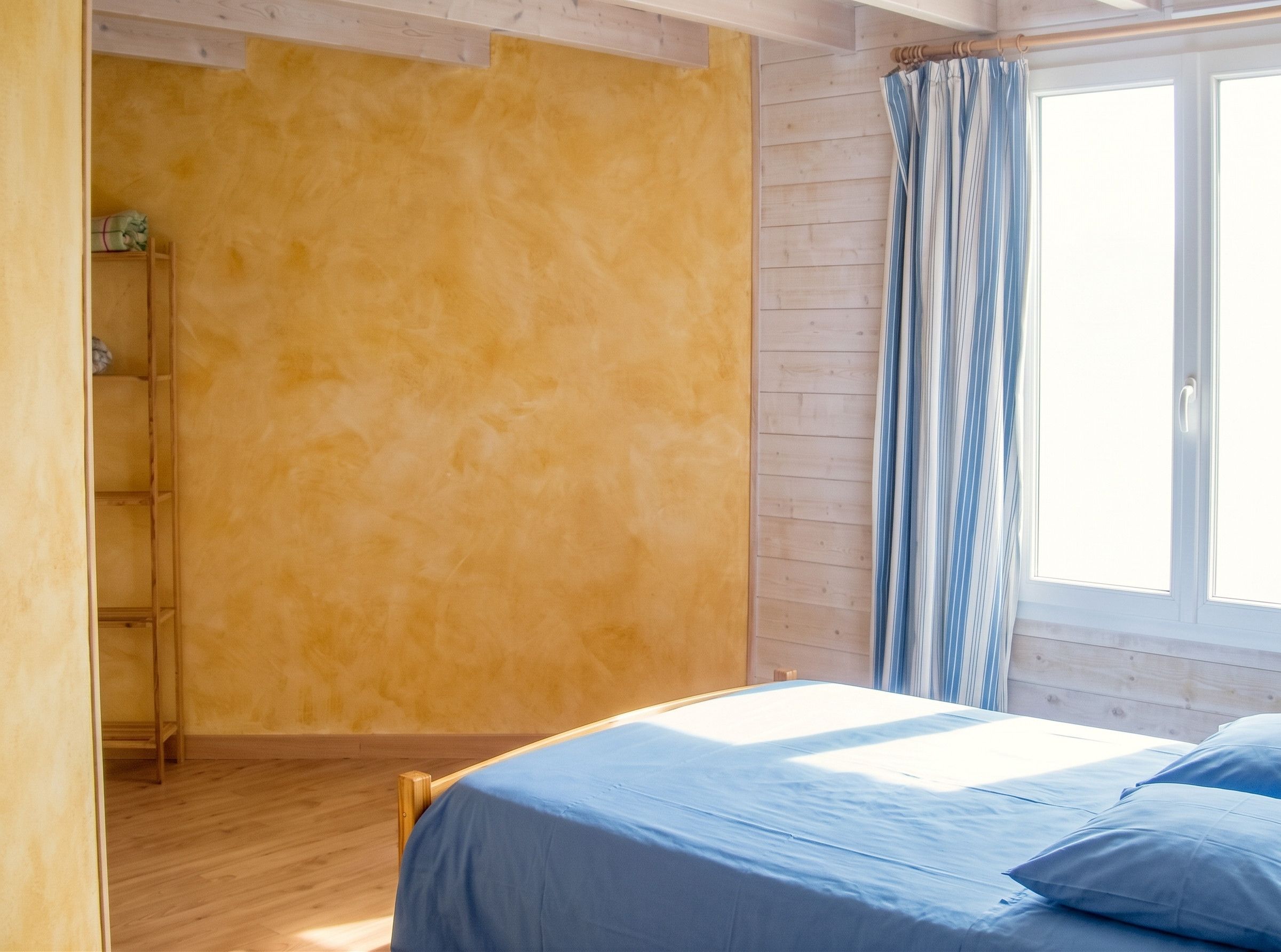 Une chambre à coucher avec un lit, une fenêtre avec des rideaux et une armoire en bois.