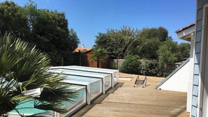 A pool area with glass-enclosed hot tubs, wooden decking, and a palm tree. - Homerez - Villa in Saint Hilaire de Riez (Saint Hilaire de Riez)