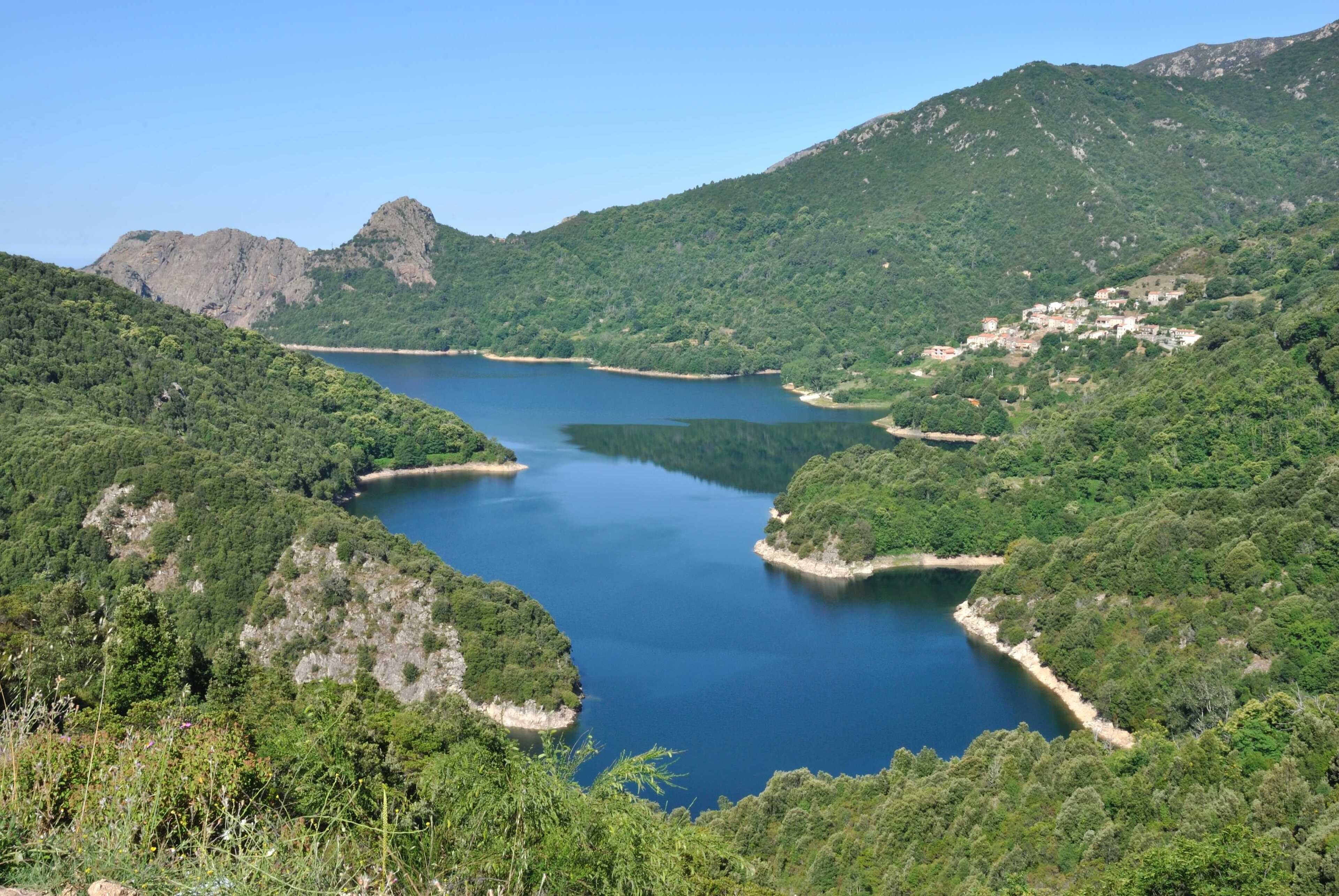 Un paysage montagneux avec un lac entouré d’une végétation luxuriante et d’un terrain rocheux.