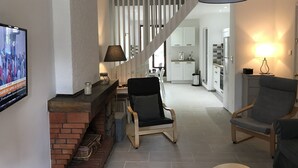 A modern living room with a fireplace, a television, and a staircase leading to a kitchen. - 12 minutes from Porticcio, charming house, 3 air-conditioned bedrooms with a garden terrace (Cauro)