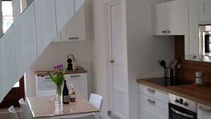 A modern kitchen with white cabinetry, a dining area with a table and chairs, and a staircase leading to an upper level. - 12 minutes from Porticcio, charming house, 3 air-conditioned bedrooms with a garden terrace (Cauro)