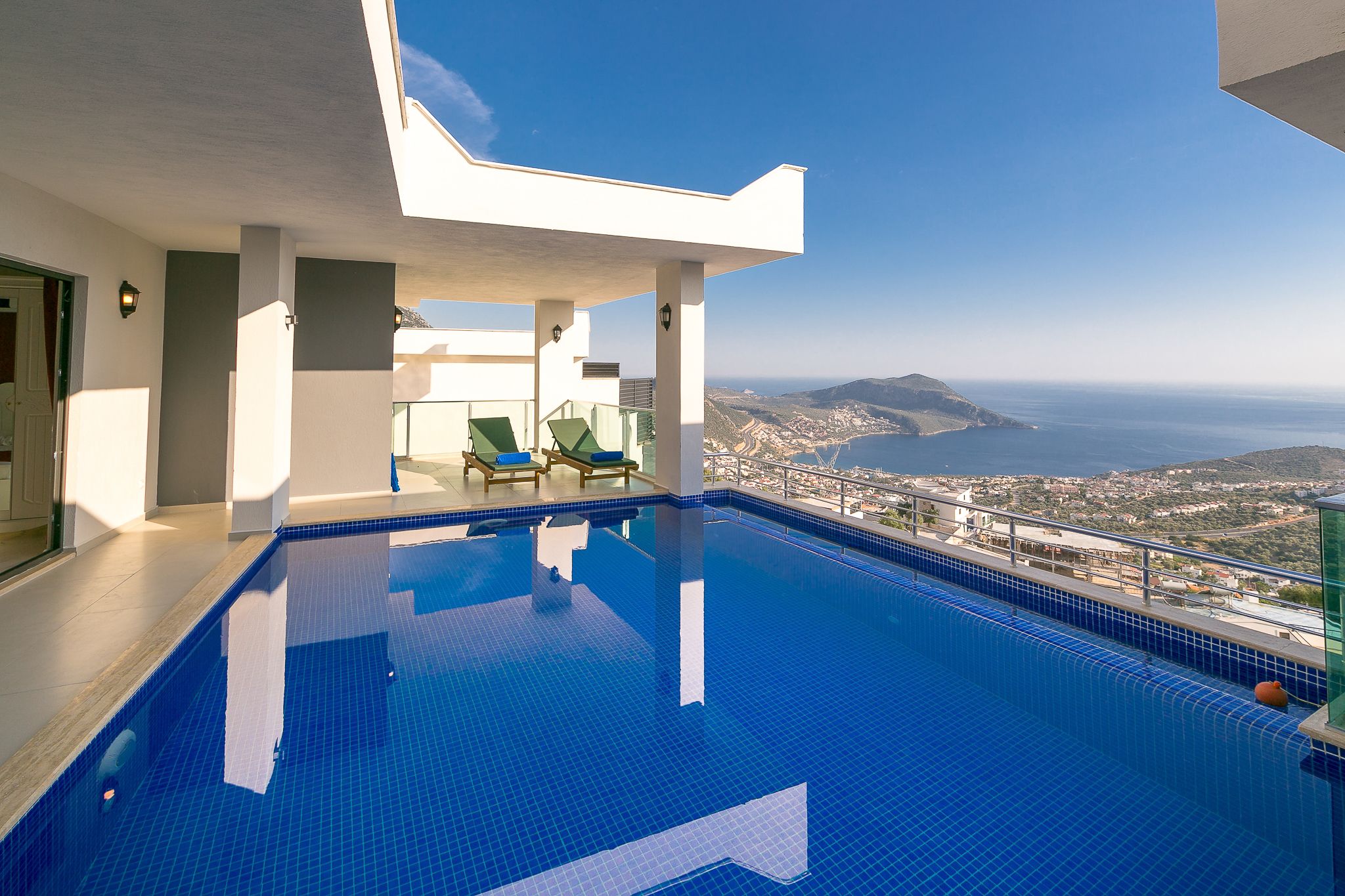 A swimming pool with a clear view of the sea and hills.