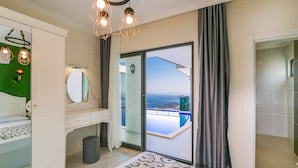 Une chambre avec un lit, une coiffeuse, un miroir, une commode et un balcon donnant sur la piscine.