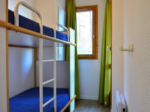 Ein Schlafraum mit Etagenbetten, einem Fenster und Vorhängen.