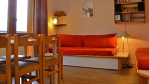 Un accogliente soggiorno con un divano in legno, una poltrona, una lampada e una libreria.