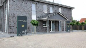 A two-story brick building with a covered entrance and a sign that reads "Kleinsche Hof Gastehaus." - Köhncke's Landgasthof und Hotel (Wiefelstede)