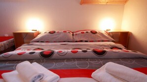 Ein ordentlich bezogenes Bett mit gemusterten Bettwäsche und Kissen, zwei Nachttische und aufgerollte Handtücher auf dem Bett.