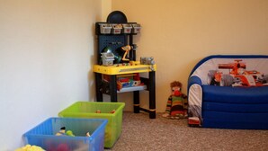 Ein Kinderzimmer mit Spielzeug-Werkbank, Aufbewahrungsboxen und einem Bett mit Rennauto-Bettwäsche.