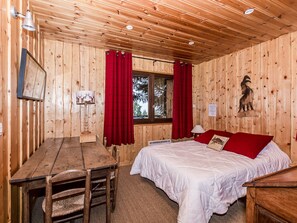 Une pièce dans un chalet en bois, comprenant un lit, une table et une chaise.