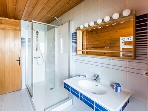 A modern bathroom with a glass shower enclosure, a wooden ceiling, and a white sink with blue tiles. - Chalet spacieux, 3 niveaux, 10 personnes, 4 chambres, proche pistes et centre, Wi-Fi, parking gratuit. (Bellentre)