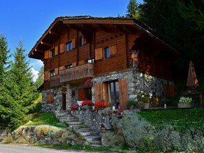 Chalet-style building with a balcony and stone steps leading up to the entrance.