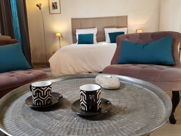 A hotel room with a bed, two sofas, a coffee table with two cups, and a nightstand with a lamp. - Very comfortable independent studio of 30 m2, in a 19th century presbytery. (Tarascon)
