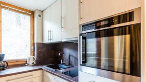 Uma cozinha moderna com armários brancos, forno de aço inoxidável e uma pia embutida.